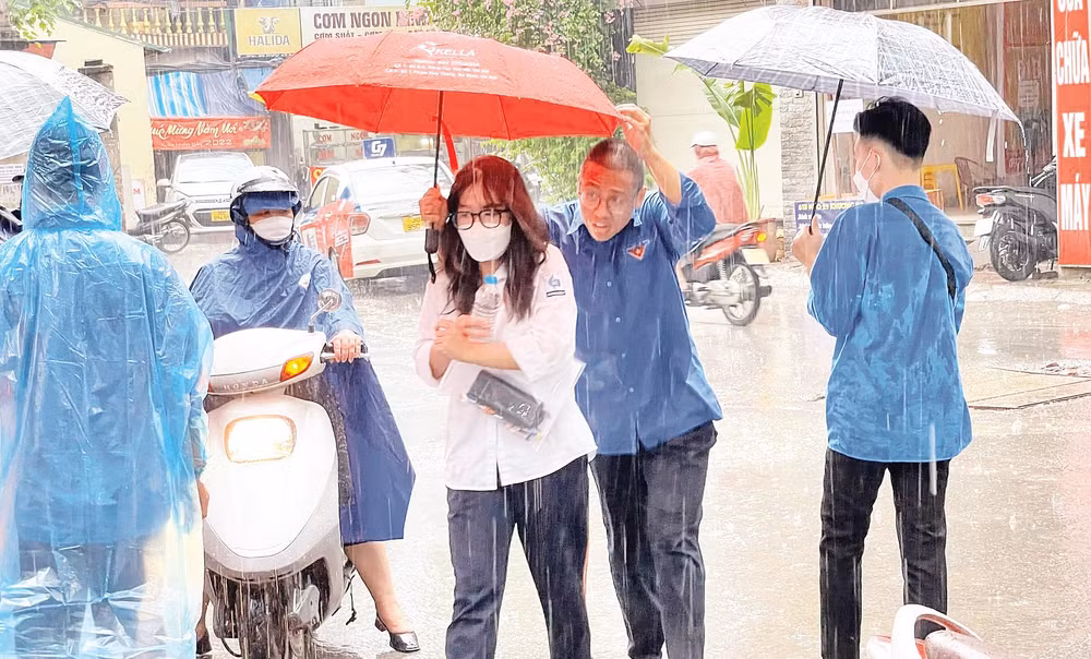 Thanh niên tình nguyện che ô, hỗ trợ thí sinh vào phòng thi.