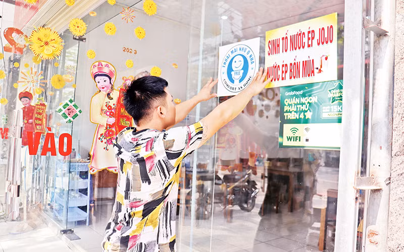 Nhân viên một cơ sở du lịch ở Đà Nẵng dán biểu tượng xã hội hóa nhà vệ sinh công cộng tại khu vực dễ thấy. (Ảnh Thanh Tâm)