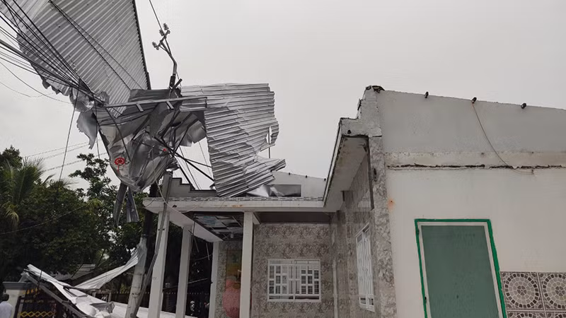 Mái nhà bị dông lốc cuốn còn vướng trên đường dây điện. Mái nhà bị dông lốc cuốn còn vướng trên đường dây điện.
