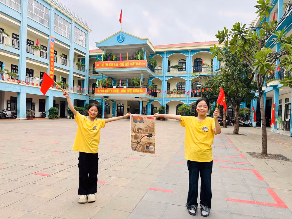 Em Thùy Anh và Kiều Anh, lớp 5A6 thích thú check-in với tờ Báo.
