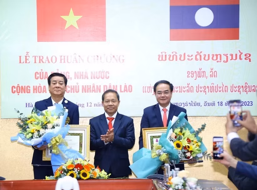 Ông Khamlay Sipraseuth, Ủy viên Trung ương Đảng, Phó Chủ tịch thường trực Ủy ban Trung ương Mặt trận Lào Xây dựng đất nước trao tặng Huân chương Itxala (Tự do) hạng III cho Thứ trưởng Bộ Nội vụ Vũ Chiến Thắng (bên phải) và nguyên Thứ trưởng, nguyên Phó Chủ nhiệm Ủy ban Dân tộc Hoàng Xuân Lương (bên trái). (Ảnh: Văn Điệp/TTXVN)