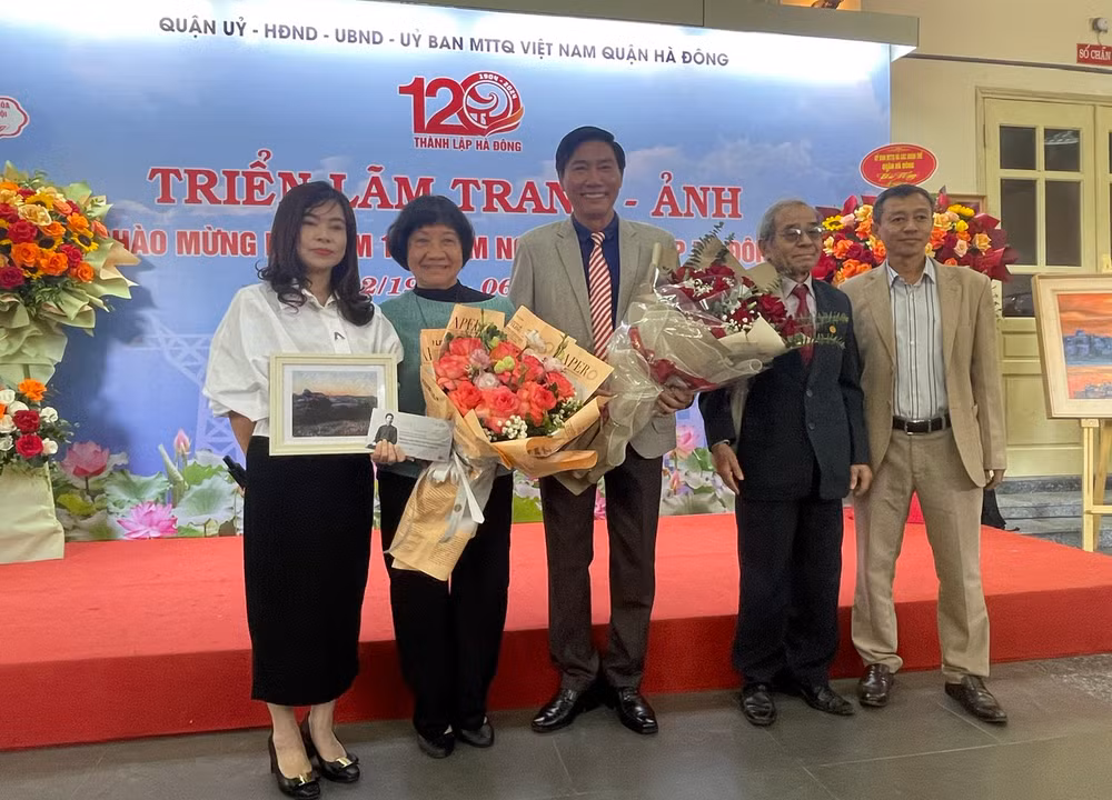Họa sĩ Đặng Thị Khuê, nguyên đại biểu Quốc hội khóa VII, nguyên Thư ký Hội nghệ sĩ tạo hình Việt Nam tặng hoa, quà cho họa sĩ Nguyễn Văn Trường.