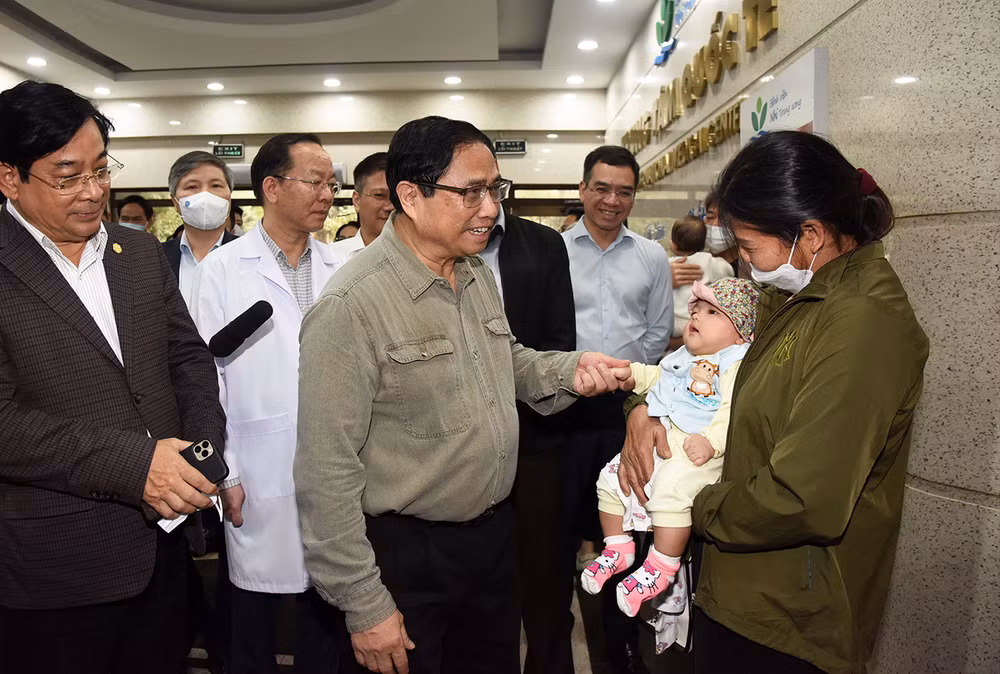 Thủ tướng hỏi thăm sức khỏe một trẻ đang khám tại Bệnh viện Nhi Trung ương trong thời điểm thời tiết chuyển mùa.