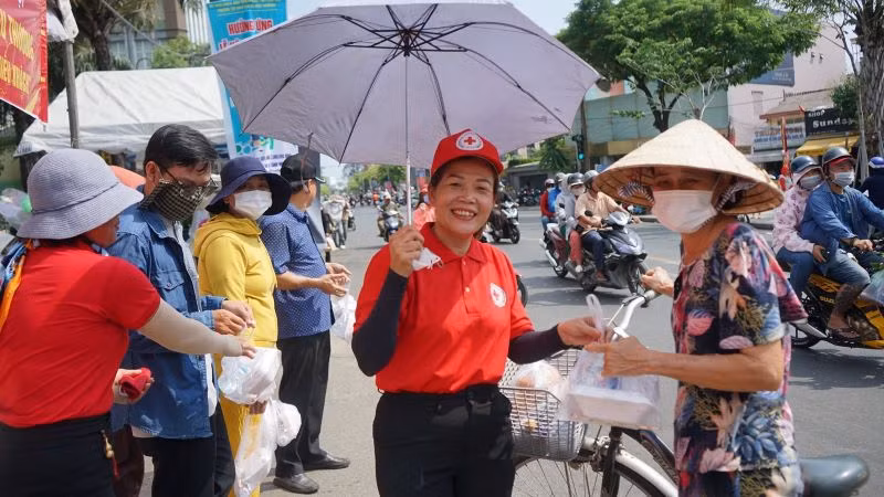 Các thành viên Hội chữ thập đỏ thành phố Thủ Dầu Một phát thức ăn miễn phí cho người dân đến lễ hội.