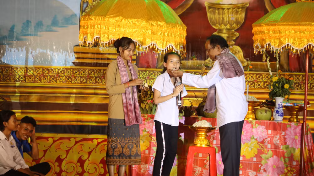 Các nghệ nhân chùa Khmer xã Bình Phú, huyện Càng Long kể câu chuyện ý nghĩa lễ cúng trăng và thực hiện nghi thức đút cốm dẹp cho trẻ em.