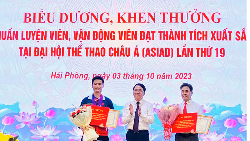 Lãnh đạo Ủy ban nhân dân thành phố Hải Phòng trao Bằng khen và tiền thưởng tặng vận động viên Phạm Quang Huy (trái) và huấn luyện viên Phạm Cao Sơn (phải).