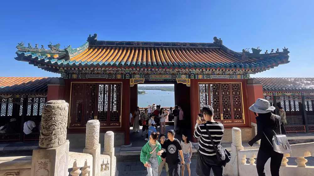 Du khách lưu lại hình ảnh Di Hòa viên thu nhỏ qua cổng Phật Hương các. (Ảnh: HỮU HƯNG)