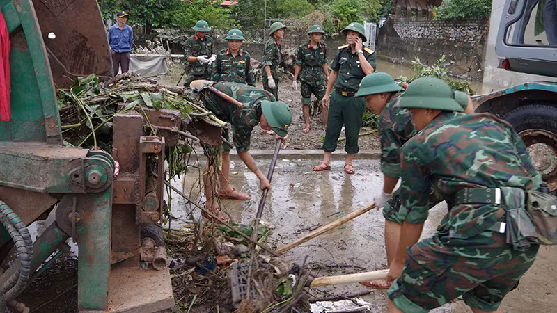 Bộ đội tham gia làm vệ sinh môi trường ở khu dân cư từng ngập nước.