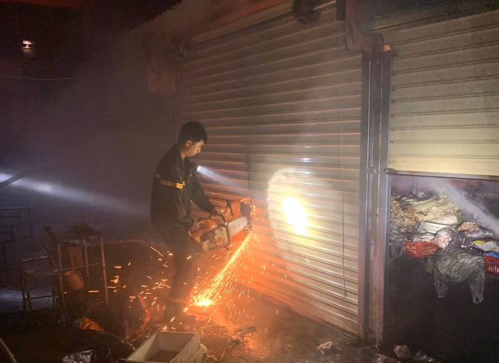 Lực lượng chức năng phải dùng cưa cưa cửa cuốn các ki-ốt trong chợ thị xã Buôn Hồ chữa cháy.