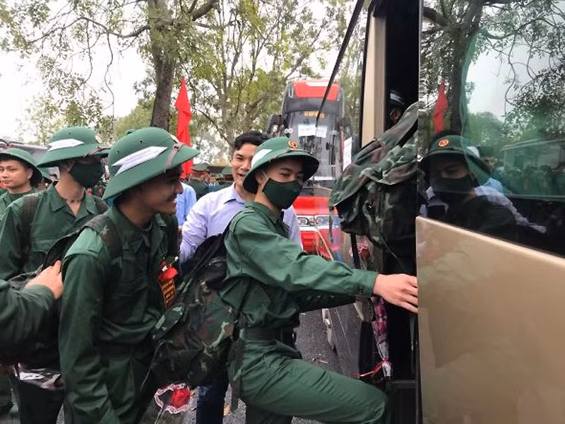 Các thanh niên phấn khởi khi lên đường thực hiện nghĩa vụ quân sự trong sự đưa tiễn của người dân và người thân.