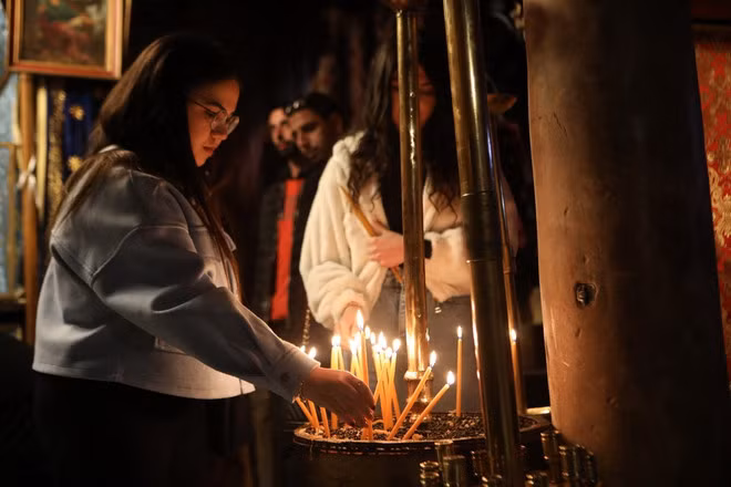 Người dân thắp nến tại Nhà thờ Giáng sinh ở Bethlehem, Bờ Tây, ngày 22/12/2024. (Nguồn: THX/TTXVN)