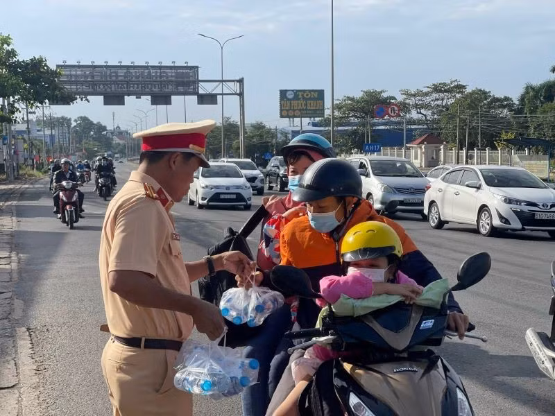 Lực lượng Cảnh sát giao thông phát nước giúp người tham giao thông trên đường về quê đón Tết Nguyên đán 2023. 