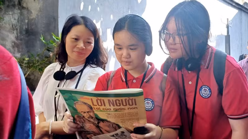 Cô giáo và học sinh trường THCS Chu Văn An (Tây Hồ, Hà Nội) đọc Báo Nhân Dân trong không gian Di tích Nhà tù Hỏa Lò.