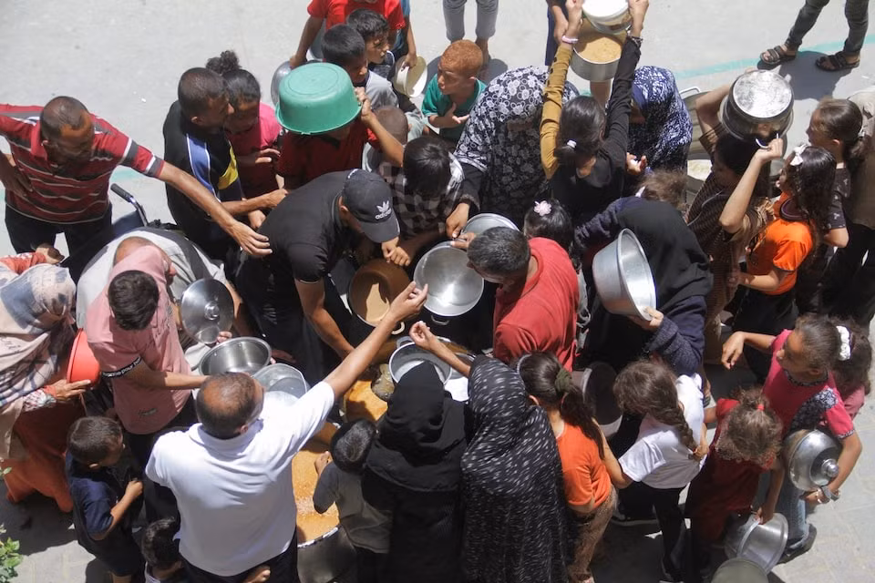 Người dân Palestin nhận đồ ăn từ thiện. Ảnh: Reuters