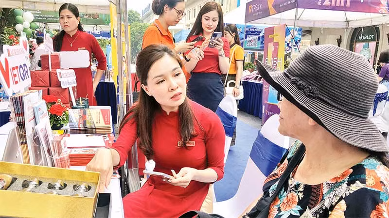 Cán bộ ngân hàng hướng dẫn người dân cách thanh toán không dùng tiền mặt.