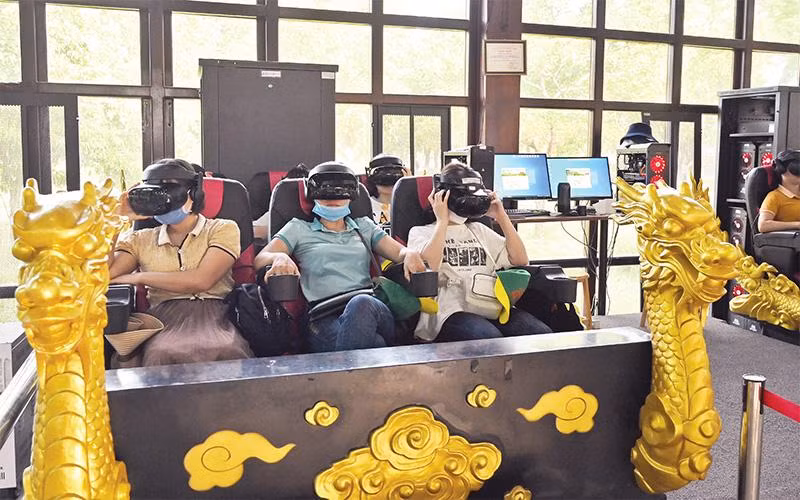 Du khách trải nghiệm dịch vụ giải trí sử dụng công nghệ thực tế ảo VR3D tại Di tích Cố đô Huế. (Ảnh DUY ÐĂNG) 