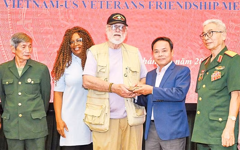 Phó Tổng Biên tập Báo Nhân Dân Ðinh Như Hoan tiếp nhận di vật liệt sĩ từ cựu chiến binh Mỹ Steve Edmunds. (Ảnh ÐĂNG ANH) 