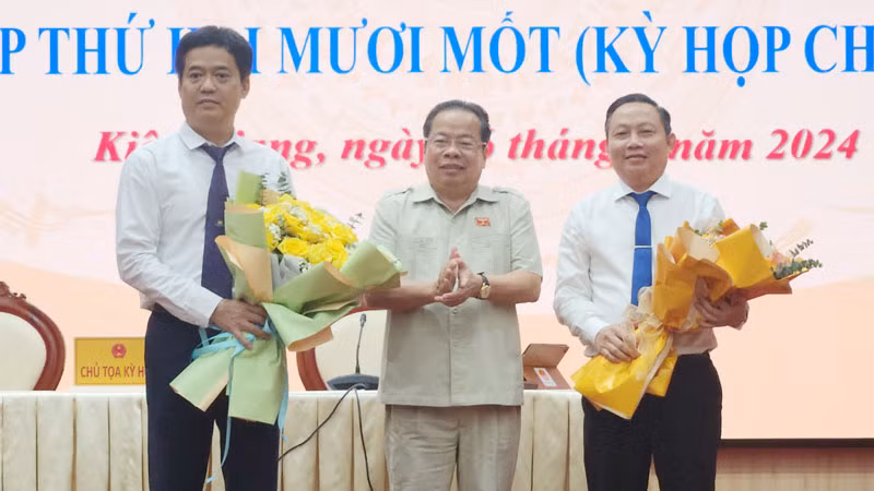 Chủ tịch Hội đồng nhân dân tỉnh Kiên Giang Mai Văn Huỳnh tặng hoa chúc mừng ông Lê Quốc Anh (bìa trái) và ông Lê Hữu Toàn (bìa phải).
