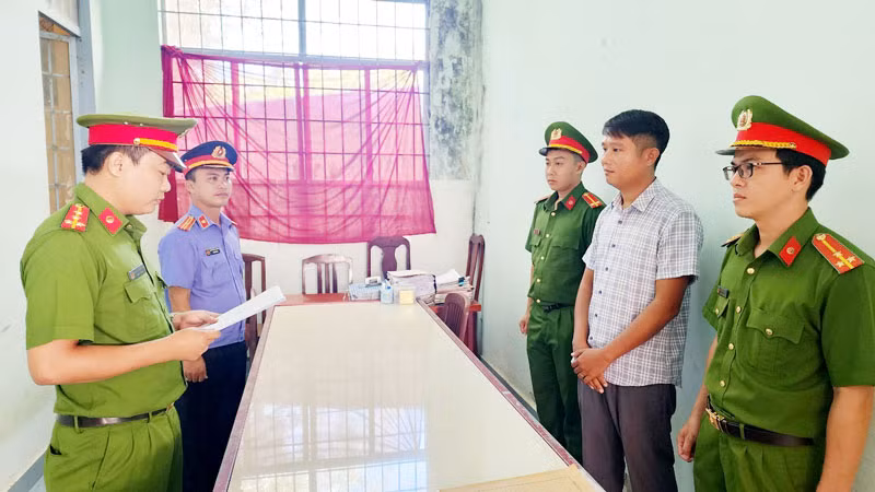 Điều tra viên tống đạt lệnh bắt tạm giam 4 tháng đối với Lê Minh Điệp (áo sơ mi sọc), giám đốc Công ty trách nhiệm hữu hạn tư vấn đầu tư và phát triển LHĐ. (Ảnh: VĂN VŨ)