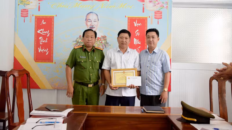 Đại diện Công an huyện Vĩnh Thuận và lãnh đạo xã Vĩnh Bình Bắc trao giấy khen cho anh Nguyễn Xuân Trọn. (Ảnh: Công an xã Vĩnh Bình Bắc cung cấp)