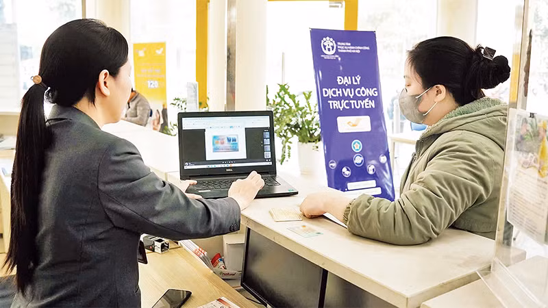 Người dân được nhân viên hướng dẫn làm thủ tục hành chính tại các đại lý dịch vụ công trực tuyến của thành phố Hà Nội.