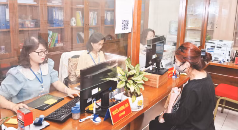 Công chức tại Bộ phận một cửa UBND phường Hàng Bài giải quyết thủ tục hành chính cho người dân. (Ảnh Duy Linh)