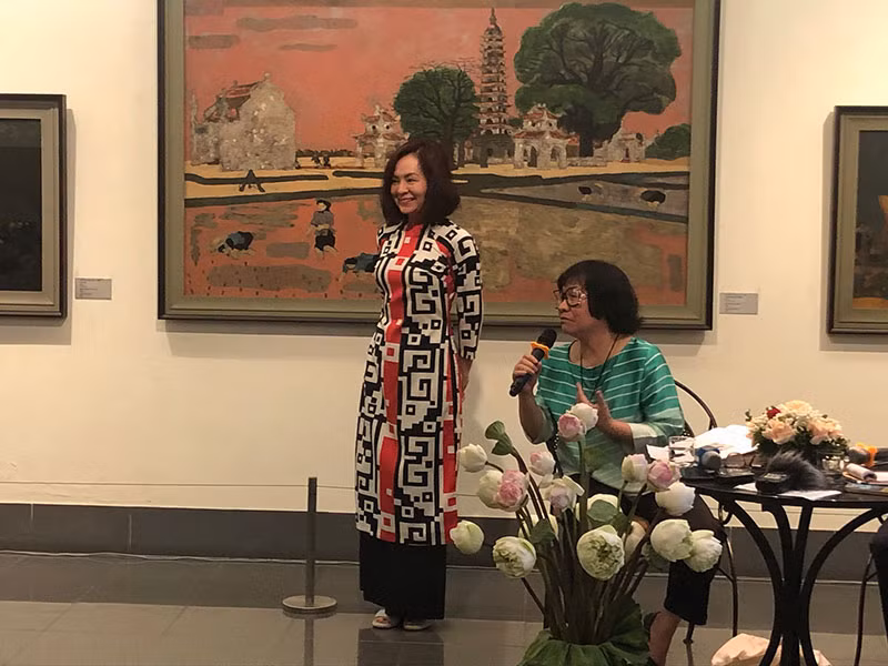Họa sĩ Đặng Thị Khuê giới thiệu chiếc áo dài 40 năm trước tại triển lãm cá nhân của họa sĩ Nguyễn Sáng, nay được con gái bà mặc lại.
