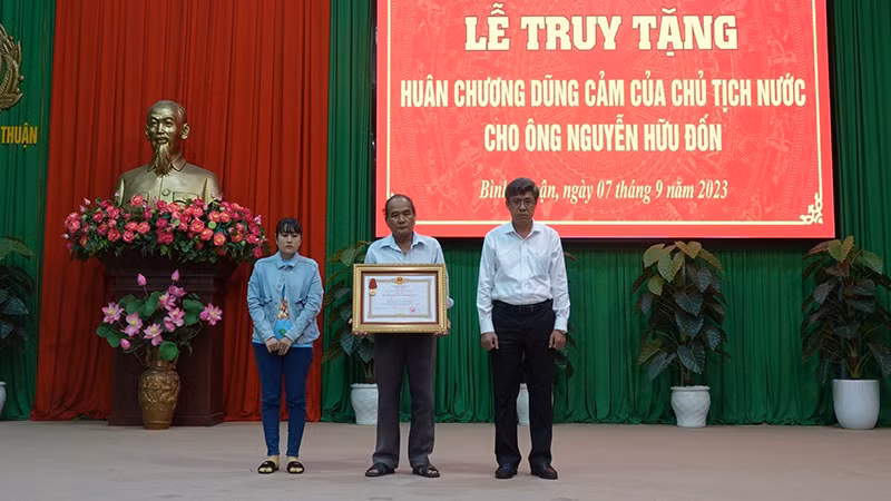 Thân nhân gia đình anh Nguyễn Hữu Đốn (vợ và cha bên trái hình) nhận Huân chương Dũng cảm của Chủ tịch nước truy tặng (Ảnh: CACC)