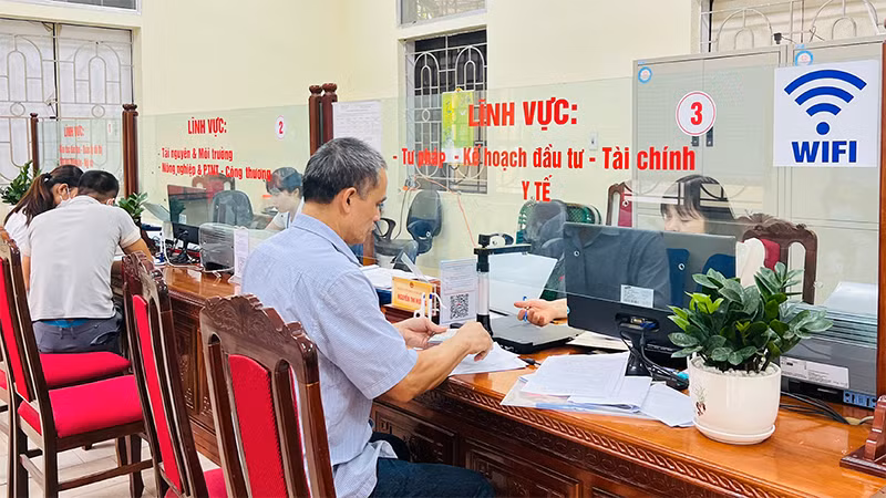 Cán bộ bộ phận một cửa huyện Ba Vì hỗ trợ người dân đến làm thủ tục hành chính. 
