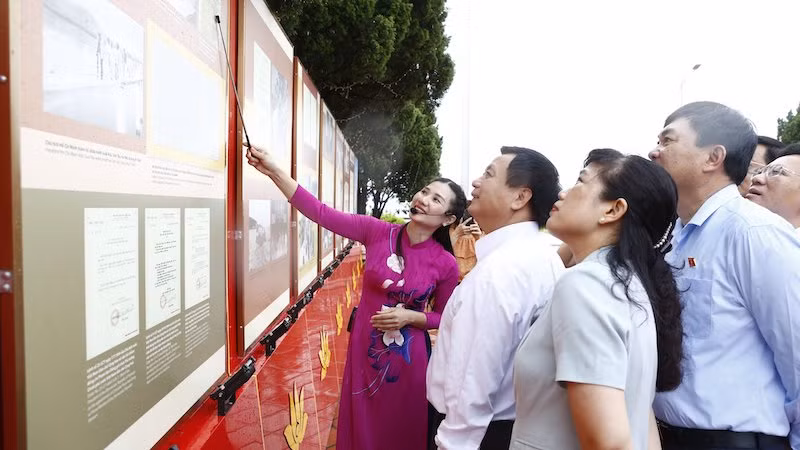 Đồng chí Nguyễn Xuân Thắng và các đại biểu tham quan và nghe giới thiệu về Triển lãm "Sưu tầm chữ ký và bút tích của Chủ tịch Hồ Chí Minh" trên đảo Cô Tô.