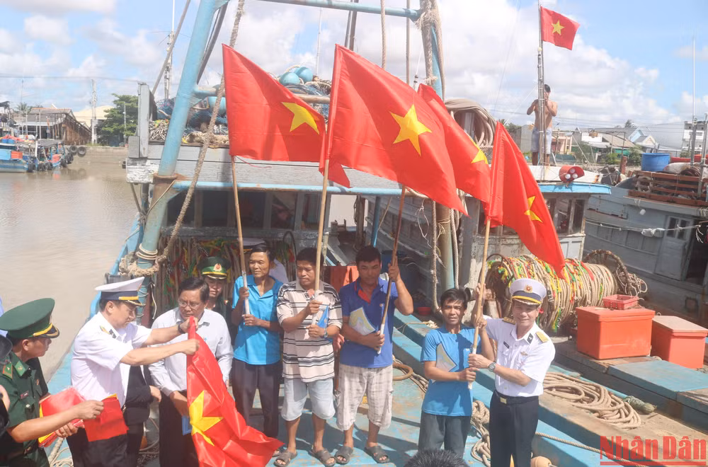 Cán bộ, chiến sĩ Vùng 2 Hải quân tặng cờ Tổ quốc cho các chủ phương tiện tàu cá đánh bắt xa bờ tại thị trấn Định An, huyện Trà Cú, tỉnh Trà Vinh.