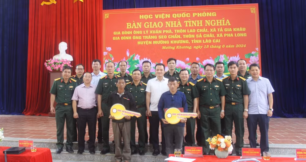 Các đại biểu chụp ảnh lưu niệm cùng 2 gia đình được nhận bàn giao “Nhà tình nghĩa”.