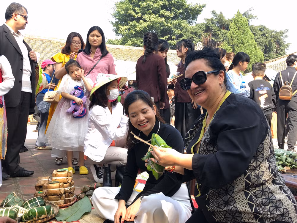 Khách nước ngoài thích thú thử gói bánh chưng.