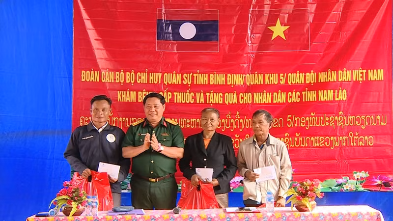 Đại tá Nguyễn Xuân Sơn, Phó Chính ủy Bộ Chỉ huy Quân sự tỉnh Bình Định tặng quà cho nhân dân ở cụm bản La Nhao, huyện Xá Mắc Khi Xay, tỉnh Attapu.