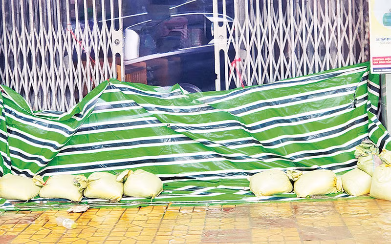 Người dân dùng bạt ni-lông, bao cát ngăn nước tràn vào nhà. 