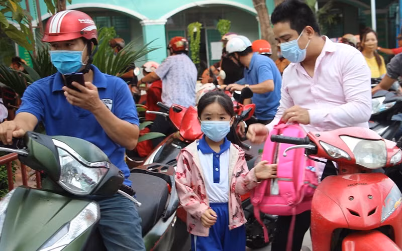 Nhiều trẻ em được bố mẹ đưa đến trường bằng xe máy. (Ảnh Ngọc Biểu)