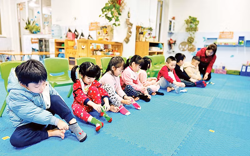 Cô giáo Trường mầm non số 6 (quận Ba Đình) hướng dẫn trẻ cách giữ ấm cơ thể khi trời lạnh.