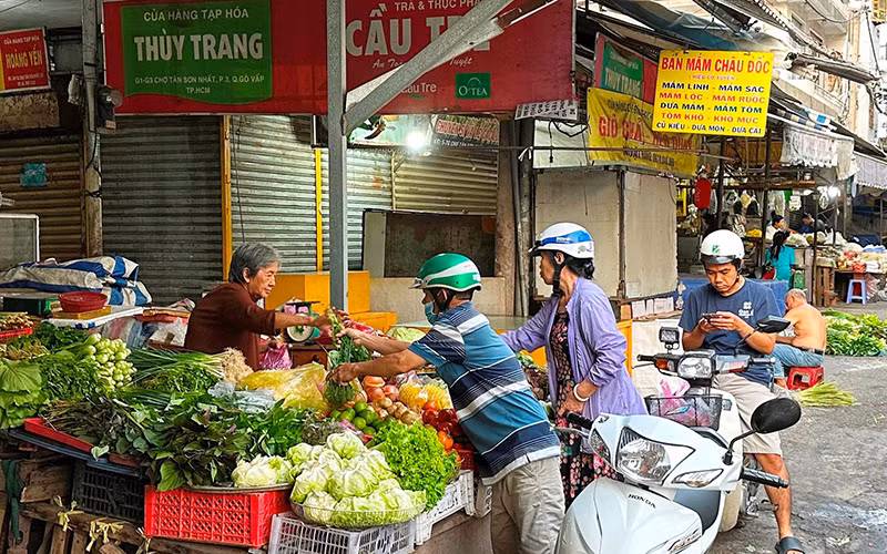 Người dân mua rau quả tại chợ Tân Sơn Nhất trong sáng mồng 4 tháng Giêng. (Ảnh HOÀNG LIÊM)