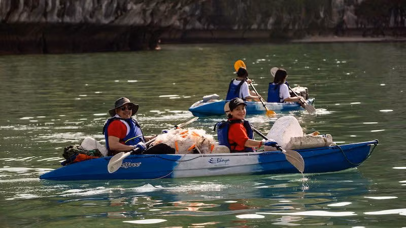 Các tình nguyện viên chèo kayak đi vớt rác trôi nổi trên biển.
