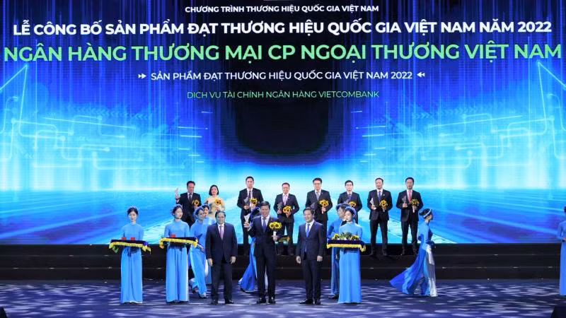Thủ tướng Chính phủ Phạm Minh Chính (hàng đầu thứ 3 từ trái sang) trao Biểu trưng và đồng chí Nguyễn Hồng Diên - Bộ trưởng Công thương, Chủ tịch Hội đồng Thương hiệu quốc gia Việt Nam (hàng đầu thứ 2 từ phải sang) tặng hoa cho đồng chí Phạm Mạnh Thắng - Phó Tổng Giám đốc Vietcombank.