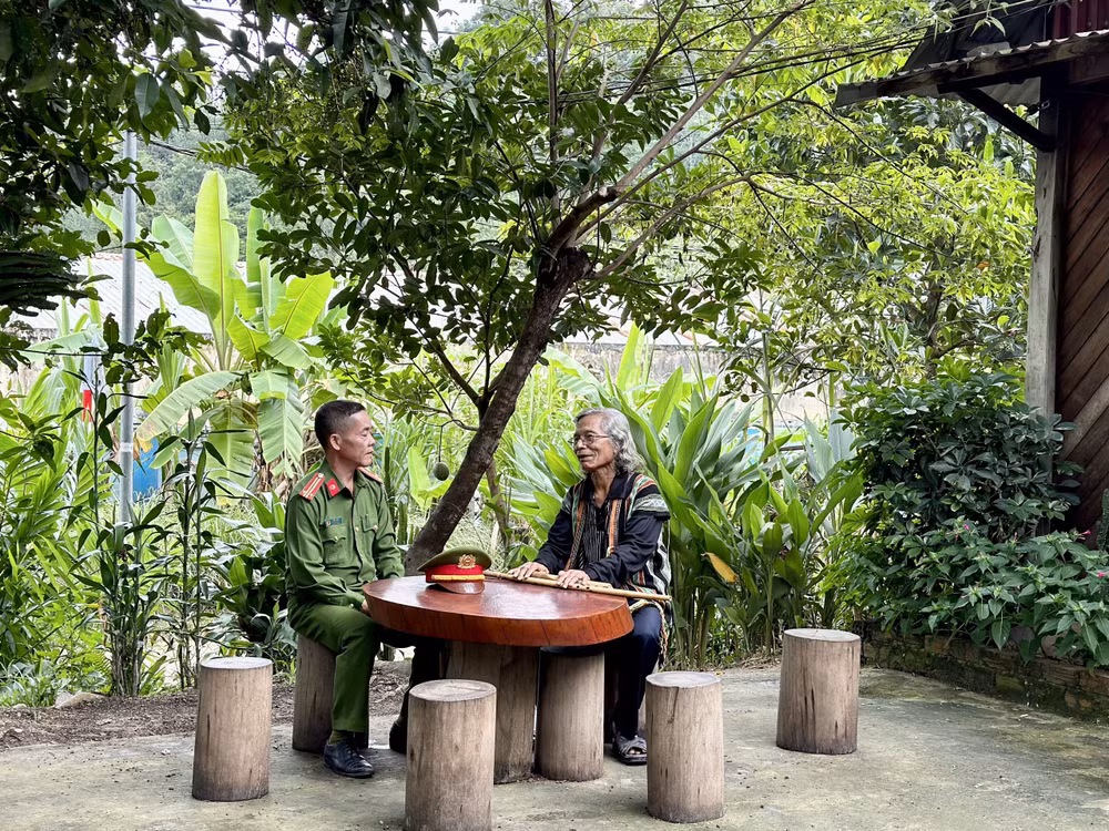 Trung tá Ating Chơn trao đổi với già làng Bríu Pố về công tác giữ gìn an ninh trật tự.