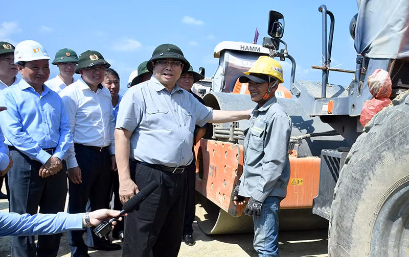 Thủ tướng Phạm Minh Chính hỏi thăm một công nhân lái xe lu đang thi công tại Dự án đường bộ cao tốc Vân Phong-Nha Trang.