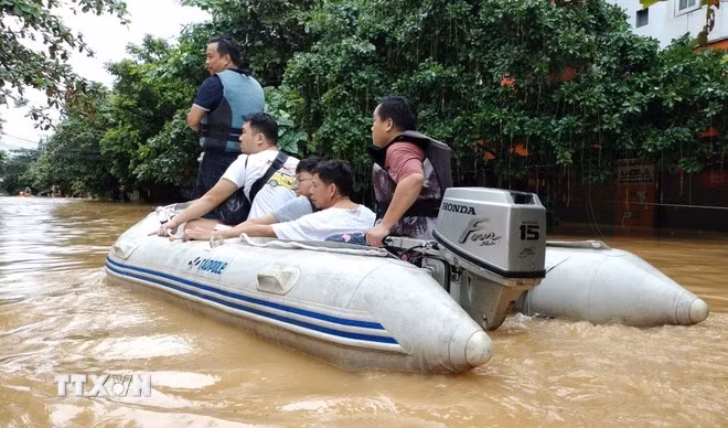 Lực lượng cứu hộ đưa người dân ra khỏi khu vực ngập lụt. (Ảnh: Tuấn Anh/TTXVN)