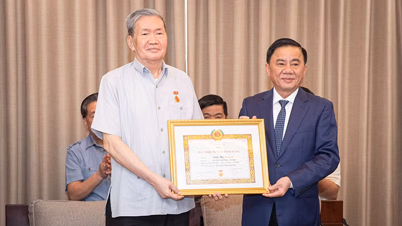 Đồng chí Trần Cẩm Tú trao Quyết định tặng Huy hiệu 50 tuổi Đảng cho đồng chí Đinh Thế Huynh. (Ảnh: SƠN TÙNG)