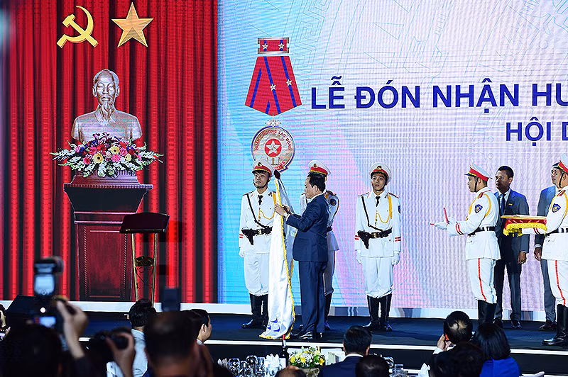 Phó Thủ tướng Chính phủ Trần Lưu Quang gắn Huân chương Lao động hạng Nhì lên lá cờ truyền thống của Hội Doanh nghiệp trẻ Hà Nội.