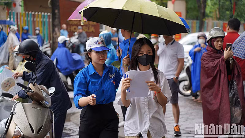 Tình nguyện viên "Tiếp sức mùa thi" năm 2023 hỗ trợ thí sinh dưới cơn mưa.