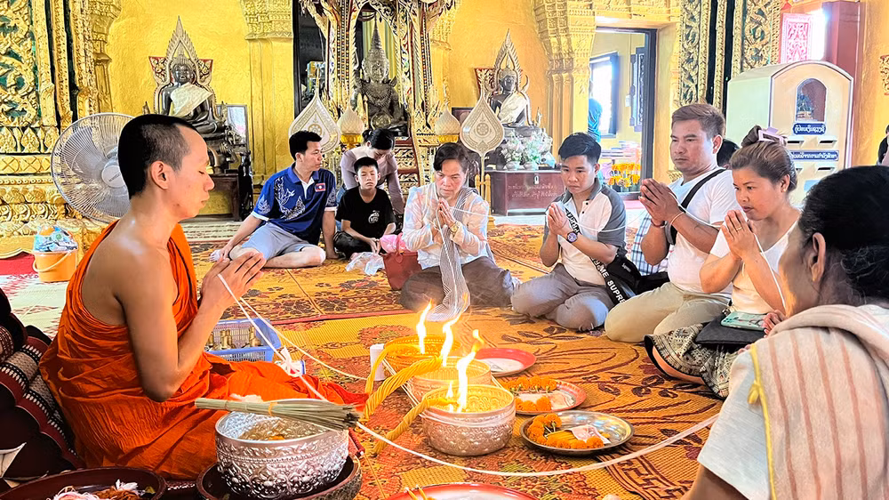 Trong dịp Bun Pi May, người dân Lào thường thực hiện nghi lễ buộc chỉ cổ tay tại các ngôi chùa để cầu an cho gia đình trong năm mới.