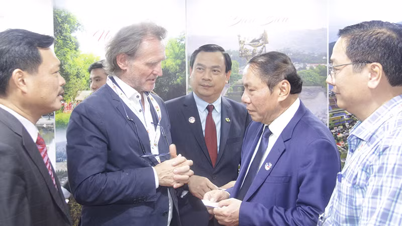 Một vị khách quốc tế trao đổi với Bộ trưởng Nguyễn Văn Hùng tại Gian hàng Du lịch Việt Nam. (Ảnh: Hải Tiến)