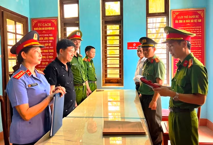 Nguyễn Quốc Trung, Giám đốc Công ty TNHH Thạch Phú Hưng (áo đen, thứ 2 từ trái sang) nghe đọc lệnh khởi tố. (Ảnh: Công an cung cấp)