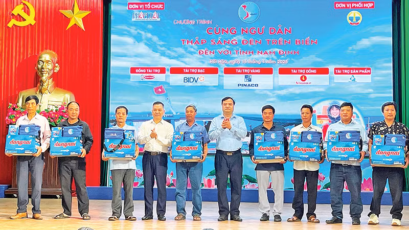 Lãnh đạo tỉnh Nam Định cùng nhà tài trợ trao bình ắc-quy, đèn led, túi thuốc và cẩm nang “Những điều cần biết về đánh bắt hải sản” tặng ngư dân.